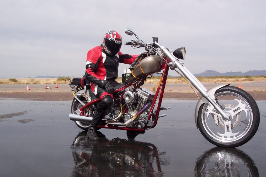 A motorcycle ride wearing a helmet sits on a motorcycle on a testing track.